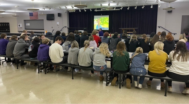 students sitting in the cafeteria and watching a presentation